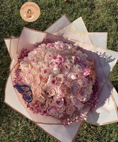 a bouquet of pink roses in a box on the grass with a butterfly and i love you card