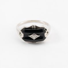 Hi. This is a pretty onyx ring with diamond accents in 10k white gold. The onyx stone measures approximately 7.5x14mm. At the center is a diamond accent. It is marked 10k on the inside of the ring. The ring finger size is 7.25. Sorry, we d not resize rings. The weight of the ring with stones is 3.4 grams. Thanks for looking. Classic Black Rings With Accent Stones, Black Oval Enamel Ring For Formal Occasions, Black Diamond Ring With Accent Stones For Formal Occasions, Formal Onyx Diamond Ring In Fine Jewelry Style, Black Oval Enamel Ring, Formal Onyx Diamond Ring Fine Jewelry, Formal White Gold Enamel Ring With Diamond Accents, Formal Black Diamond Ring With Accent Stones, Formal Black Oval Enamel Ring