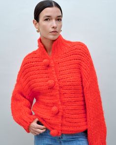 model wearing red relaxed fit cardigan with oversized buttons Fall Chunky Knit Merino Wool Cardigan, Wool Knit One-size Sweater, Wool Knit Sweater One Size, Orange Knitted Cardigan For Winter, Textured Knit Merino Wool Cardigan For Fall, Merino Wool Knit Cardigan For Winter, One Size Wool Knit Sweater, Winter Merino Wool Knit Cardigan, Fall Textured Merino Wool Cardigan