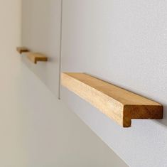 two wooden shelfs are hanging on the wall