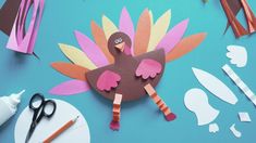 paper turkey cut out with scissors and other crafting supplies on a blue table top