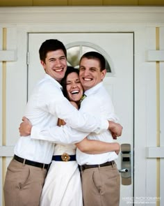 two men and a woman hugging each other in front of a door with their arms around one another