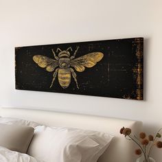 a bed with pillows and a painting on the wall above it that has a bee