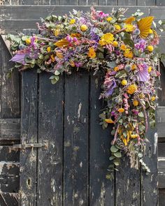 an old door decorated with flowers and greenery