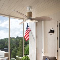 an american flag hanging from the ceiling of a screened porch with furniture and outdoor lighting