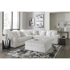 a living room with a large white sectional couch and matching footstool in front of a window