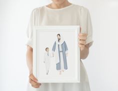 a woman holding up a framed photo with a drawing of a man and child on it