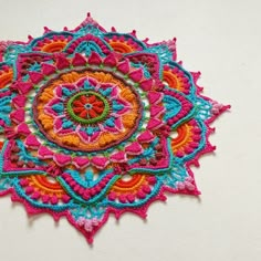 a colorful crocheted doily on a white wall