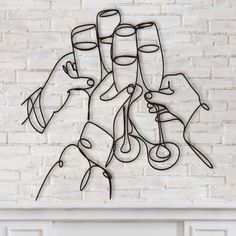 a metal wall hanging with wine glasses on it's side and two hands holding champagne flutes