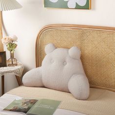 a white teddy bear pillow sitting on top of a bed next to a lamp and table