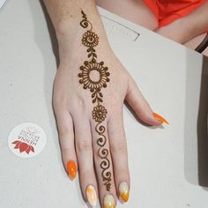 a woman's hand painted with henna on her left hand and orange nail polish