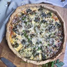 a pizza sitting on top of a wooden cutting board next to a knife and fork