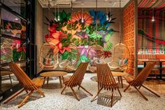 the interior of a restaurant with colorful paintings on the wall and wooden chairs around tables