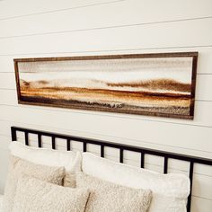 a bed with two pillows and a painting on the wall above it