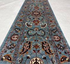 a blue rug with an intricate design on the bottom and sides is laying on a white surface