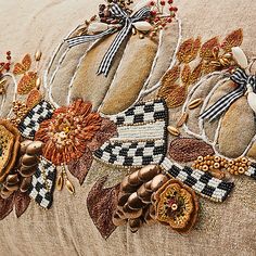 a close up of a decorative pillow on a couch with flowers and leaves embroidered onto it