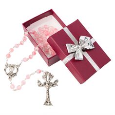 a red box with a silver cross and pink beads next to a chain that has a white bow on it