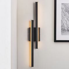 a wall mounted light that is on the side of a wall next to a framed photograph