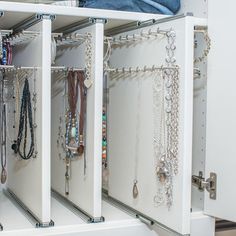 a white cabinet filled with lots of necklaces and bracelets hanging from it's sides