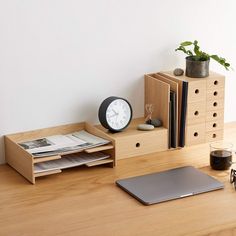 a wooden desk topped with a laptop computer next to a clock