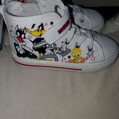 Looney Tunes Unisex Hi Top Sneaker Really Unique Item! Your Kid Will Love Them Super Cute & Stylish Synthetic Sneakers With Character Print And Round Toe, Casual White Sneakers With Character Print, Fun Sneakers With Character Print And Round Toe, White Scratch-resistant Sneakers For Spring, Spring Scratch-resistant White Sneakers, Fun Cartoon Print Sneakers With Round Toe, Spring White Scratch-resistant Sneakers, White Scratch-resistant Sneakers For Playtime, White High-top Sneakers With Cartoon Print