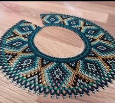 a blue and gold beaded necklace sitting on top of a wooden table