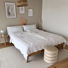 a white bed sitting in a bedroom next to two pictures on the wall above it