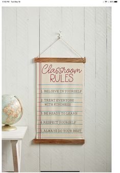 a classroom rules sign hangs on the wall next to a globe and a small table