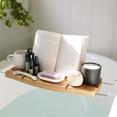 an open book sitting on top of a bath tub next to a cup and toothbrush