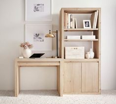 a wooden desk and bookcase in a white room with pictures on the wall behind it