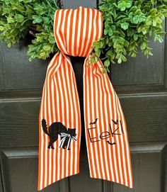 an orange and white striped scarf hanging on a door handle with the word trick written on it