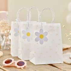 three small bags with flowers on them sitting next to some sunglasses and a pair of glasses