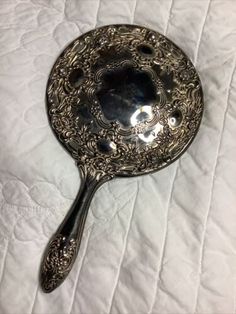 an antique spoon is sitting on a white sheet with the handle still attached to it