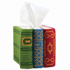 three different colored tissue boxes are stacked on top of each other