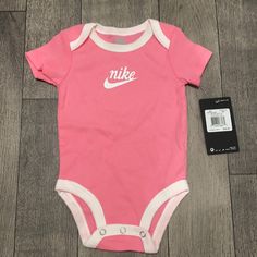 Pink & White Baby Girl Bike Onesie Casual Pink Onesie With Letter Print, Casual White Onesie For Sports, White Casual Onesie For Sports, Casual Pink Onesie For Playtime, Nike Casual Onesie For Playtime, Casual Nike Onesie For Playtime, Casual Pink Onesie For Spring, Casual White Onesie For First Birthday, Nike Baby Clothes