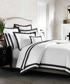 black and white bedding in a bedroom next to a nightstand with flowers on it