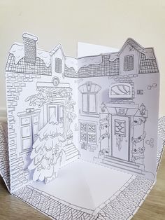 an open card with a drawing of a house on the front, and a tree in the back