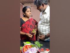 a man and woman standing in front of a table with food on top of it