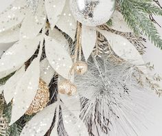 a white christmas tree with silver and gold baubles hanging from it's branches