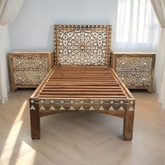 a wooden bed with intricate carvings on the headboard and foot board, in front of a window