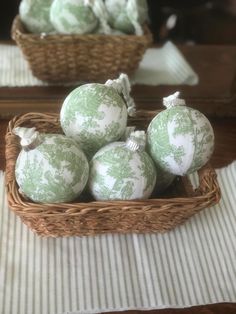 some green and white ornaments in a wicker basket on a table with striped cloth