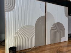 a room divider that has been decorated with white and grey circles on it, along with a black trash can in the foreground