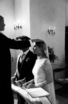 a bride and groom are getting ready for their wedding at the church in black and white