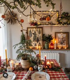 a dining room table decorated for christmas with candles and greenery on the wall above it