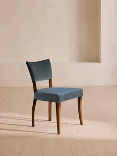 a blue chair sitting on top of a hard wood floor next to a white wall