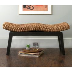 a wooden bench sitting on top of a hard wood floor next to a framed painting