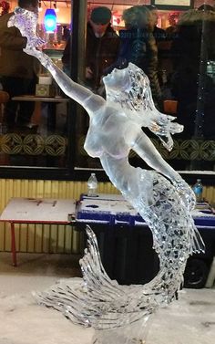 a glass sculpture of a woman holding an umbrella in front of a storefront window