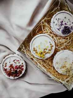 four desserts sitting in a box on top of a bed