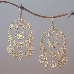 Crafted by hand elegant rope work of sterling silver bathed in 18k gold fills these queenly chandelier earrings from Bali. Desi Antari creates these circular earrings featuring accents that dangle below as well as dangling portions within. Sterling Silver Dangle Chandelier Earrings For Festive Occasions, Sterling Silver Festive Dangle Chandelier Earrings, Brass Filigree Dangle Hoop Earrings, Bohemian Gold Chandelier Earrings With Pierced Style, Ornate Gold Brass Chandelier Earrings, Elegant Brass Filigree Hoop Earrings, Ornate Pierced Brass Chandelier Earrings, Bohemian Gold Chandelier Earrings, Handmade Elegant Adjustable Chandelier Earrings