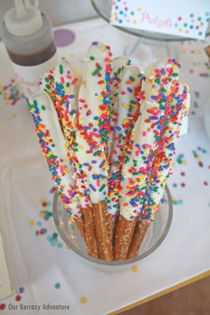 there are many sprinkles on the sticks in this glass bowl, and one is white